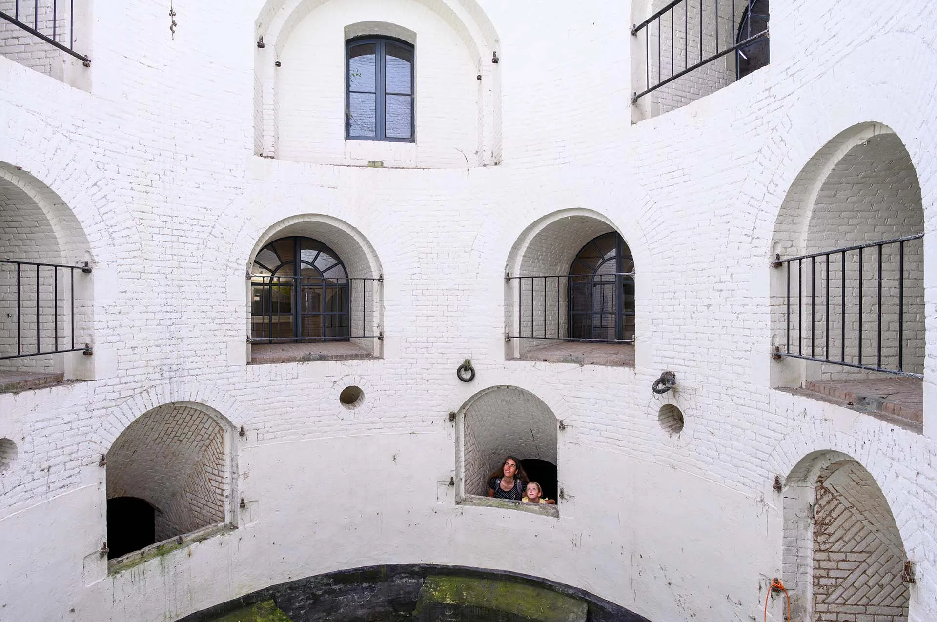 Een vrouw en haar dochter kijken uit in een lichtkoker van een historisch fort.