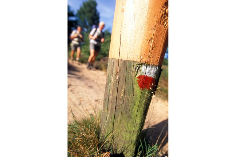 Markering van GR wandelpaden op paal, met wandelaars in achtergfrond