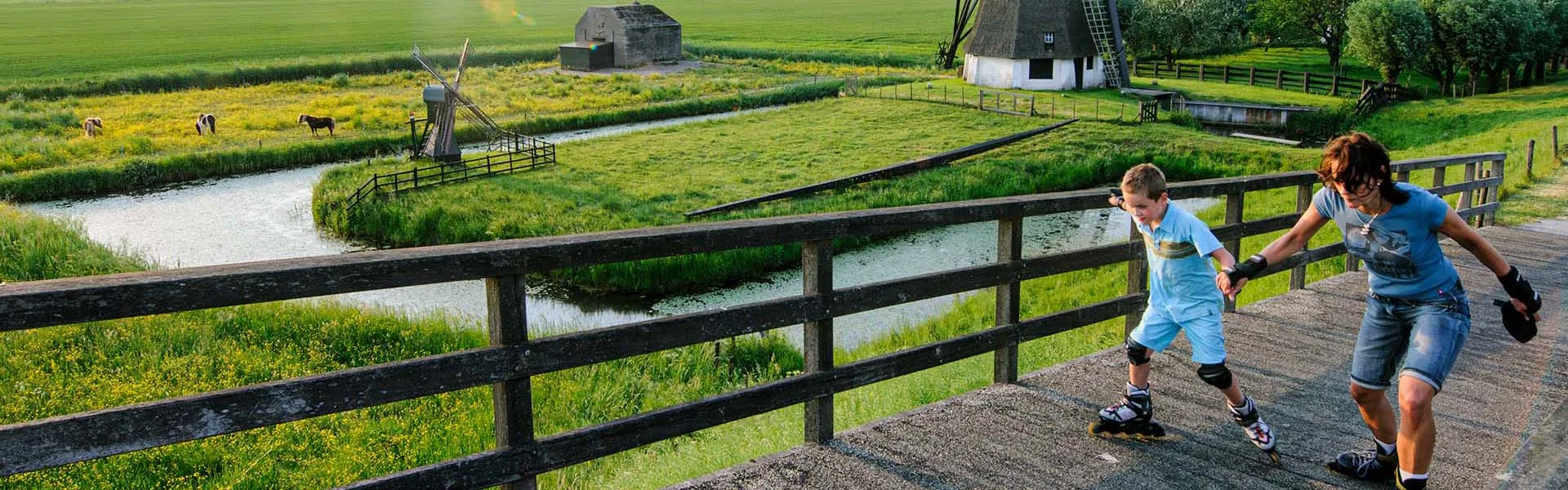 Moeder en zoon skaten over bruggetje in het Land van Altena.