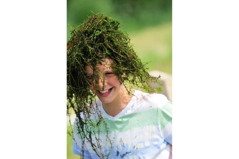 Jongen met waterplanten op hoofd.