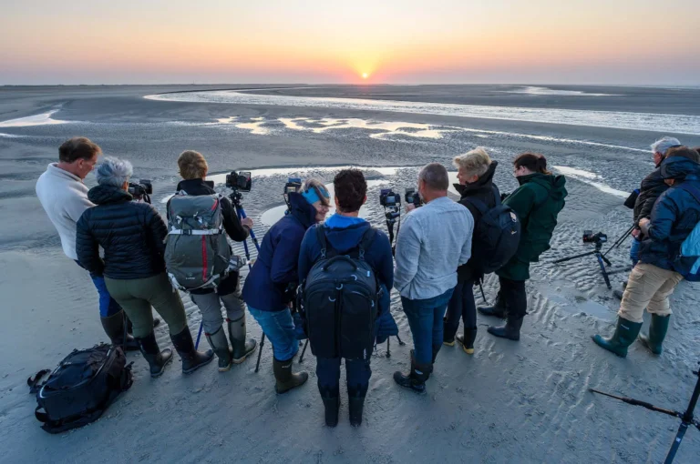 Fotografen op een strand bij zonsondergang.